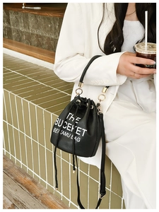 Close-up of black pebble leather bucket bag with THE BUCKET print and adjustable strap