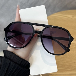 Detail of pilot-style double bridge sunglasses with purple gradient lenses and black frames