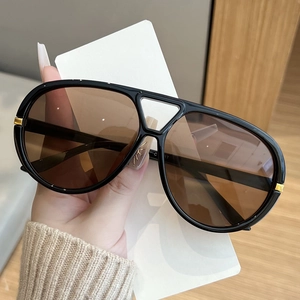 Detail of oversized aviator sunglasses with black frames and gold metal accents