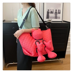 Detail of quilted bright pink tote bag with cartoon doll and adjustable black strap