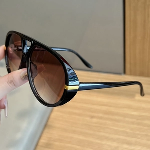 Detail view of bold aviator sunglasses with black frame and gold metal accents