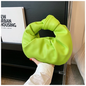 Close-up of vibrant neon green pleated knot handbag made of soft synthetic leather