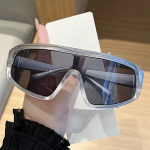Detail of oversized shield sunglasses with thick transparent grey frames and dark lenses