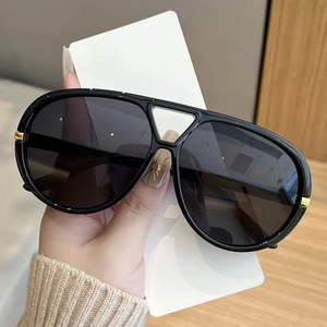 Detail view of stylish oversized black sunglasses with gold metal ring on the temple