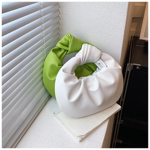 Detail of trendy knotted hobo bags in bright green and white with pleated leather textures