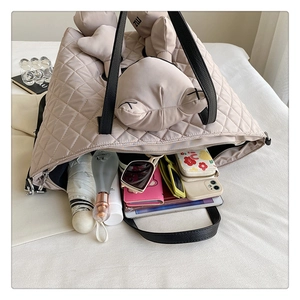 Interior view showing the large capacity of a beige quilted tote bag with essentials