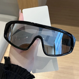 Close-up of oversized one-piece wrap-around sunglasses with glossy black frames and dark lenses
