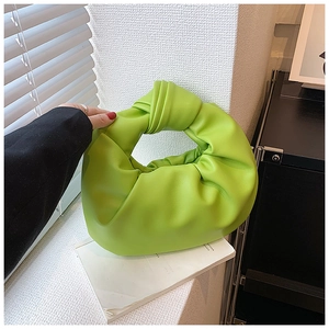 Detail of neon green pleated knot bag featuring soft PU leather texture and curved shape