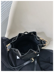 Internal view of a black drawstring bucket bag showing spacious black fabric lining