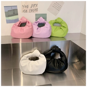 Detail of knotted handle handbags in various colors featuring soft pleated leather textures