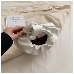 Detail of white knotted cloud bag with soft PU leather texture and magnetic closure