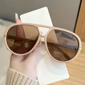 Close-up of beige oversized aviator sunglasses with gradient lenses and gold metal accents