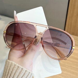 Detail view of pink gradient pilot sunglasses with translucent frames and gold metal hinges