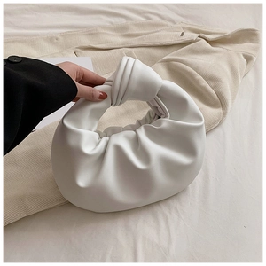 Detail shot of the white pleated cloud bag with a unique knot handle on a soft fabric base