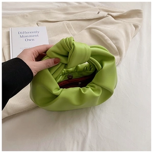 Detail of lime green knotted handbag with soft pleated texture and magnetic clasp closure