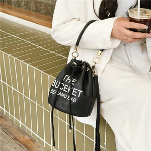 Black lychee leather drawstring bucket bag with white THE BUCKET letter print