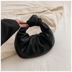 Detail of a black pleated cloud handbag featuring a knot handle and premium leather texture