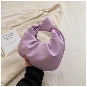 Detail of purple pleated knot handbag with soft pebble texture on corduroy background