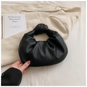 Detail of black pleated cloud bag with a unique knot handle on soft corduroy