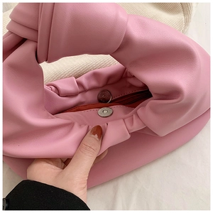 Detail view of pink pleated handbag showing magnetic snap closure and inner zipper