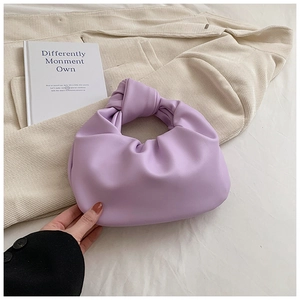Close-up of a purple pleated cloud bag with a knot handle detail on corduroy texture