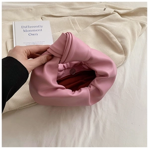 Detail of pink knotted handle handbag with magnetic closure on soft cloud pleats