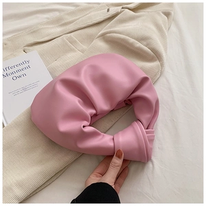 Detail of pink knotted handle on a soft pleated cloud bag made of matte vegan leather