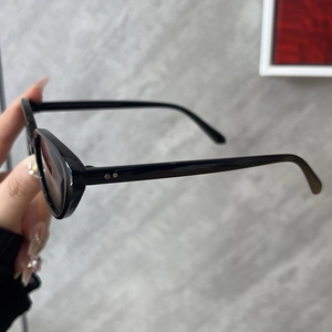 Détail des montures de lunettes de soleil ovales noires avec rivets métalliques argentés