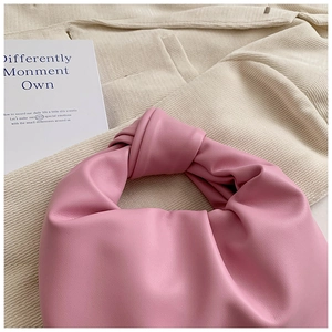 Close-up of pink knotted leather handle and soft pleated texture on handbag