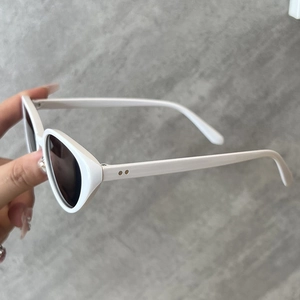 Détail de lunettes de soleil œil de chat blanches avec rivets en métal et verres foncés