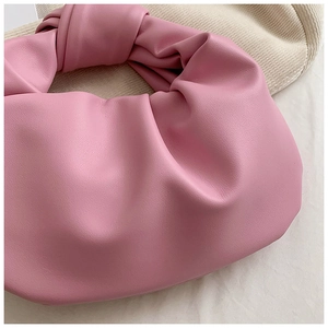 Detail shot of the soft pink knotted handle and pleated leather texture on the cloud bag