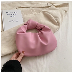 Detailed view of pink pleated handbag with knotted handle on soft corduroy background