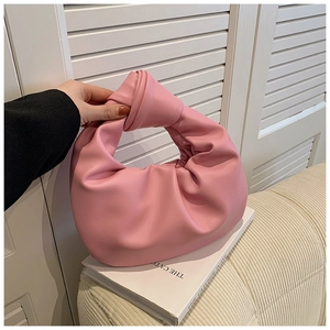Detailed view of pink knotted hobo handbag with soft pleated cloud design on white books