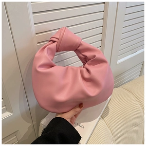 Detail of pink knotted handle on a soft pleated cloud hobo bag held by hand