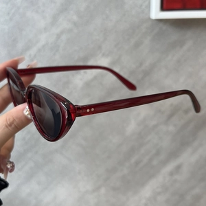Détail de lunettes de soleil œil-de-chat bordeaux avec rivets et verres anti-UV
