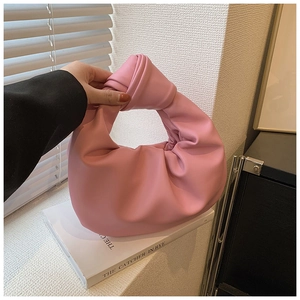Detailed shot of pink pleated cloud bag featuring soft leather texture and knot handle