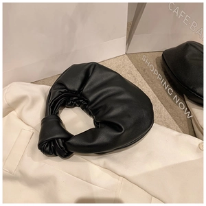 Detail of black leather knotted handle and soft pleated texture on a cloud clutch bag
