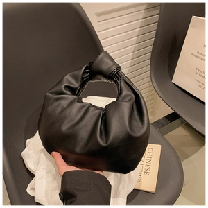 Close-up of black leather knotted handle and elegant pleated cloud bag texture