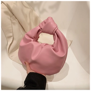 Detail of pink knotted handle on pleated croissant bag styled with a beige blazer
