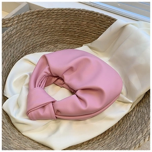 Detailed view of pink soft leather knotted clutch with elegant pleats and texture
