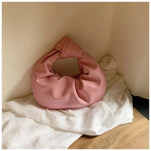 Detailed close-up of pink cloud bag with knotted handle on minimalist background