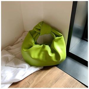 Detail view of the green knotted handle and soft pleats on a stylish cloud handbag
