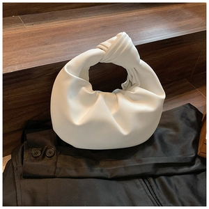 Detail of white knotted handle and pleated leather texture on a crescent handbag