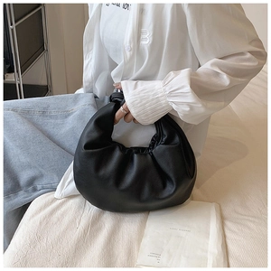 Detailed view of black pleated cloud bag featuring matte faux leather and knotted handle