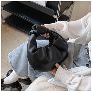 Detailed close-up of a black pleated cloud bag with a unique knotted top handle