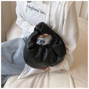 Close-up of black pleated cloud bag featuring a unique knotted handle design