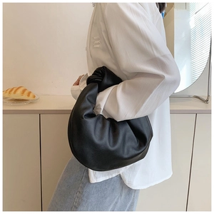 Detail of a black knotted handbag showing soft faux leather texture and minimalist style
