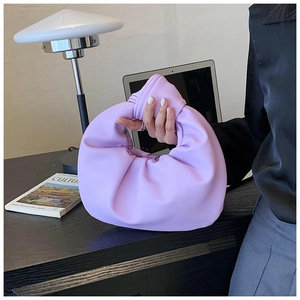 Close-up of lavender knotted handle handbag with pleated cloud design on a desk