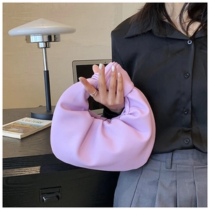 Detail of lavender knot handbag featuring soft pleated leather and a minimalist handle