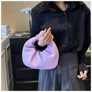 Detail of purple knotted cloud bag with pleated matte texture held by a model